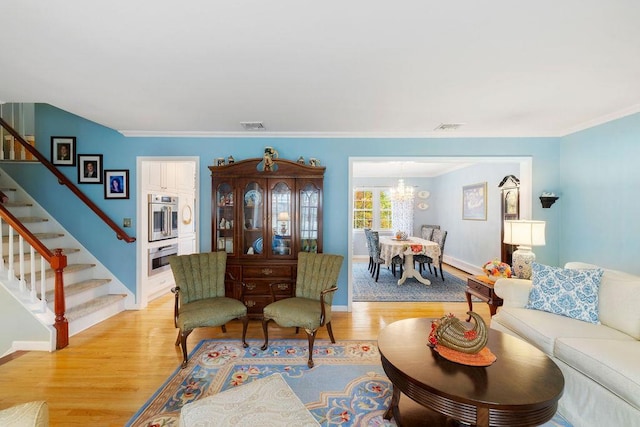 living area featuring crown molding, stairway, visible vents, and light wood finished floors