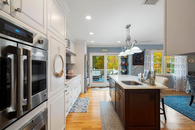 kitchen featuring a breakfast bar, white cabinets, appliances with stainless steel finishes, and a sink