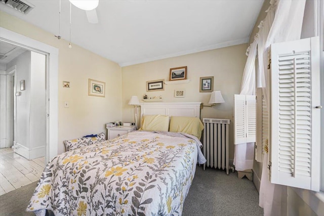 bedroom featuring ceiling fan, radiator heating unit, and dark colored carpet