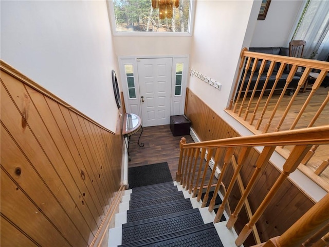 entryway with wooden walls, dark hardwood / wood-style flooring, a towering ceiling, and a chandelier