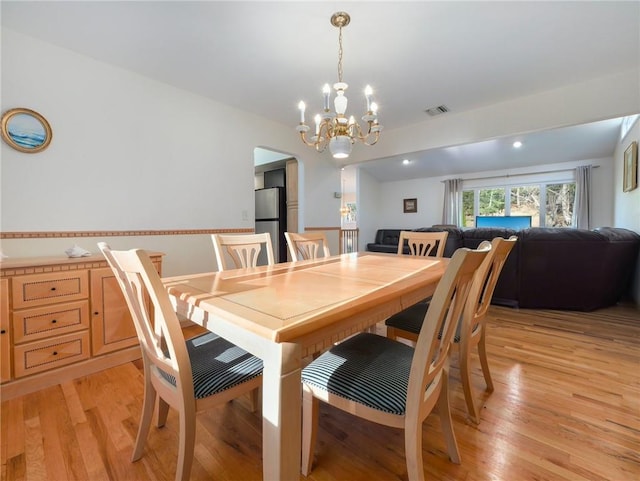 dining area featuring light wood-type flooring and a notable chandelier