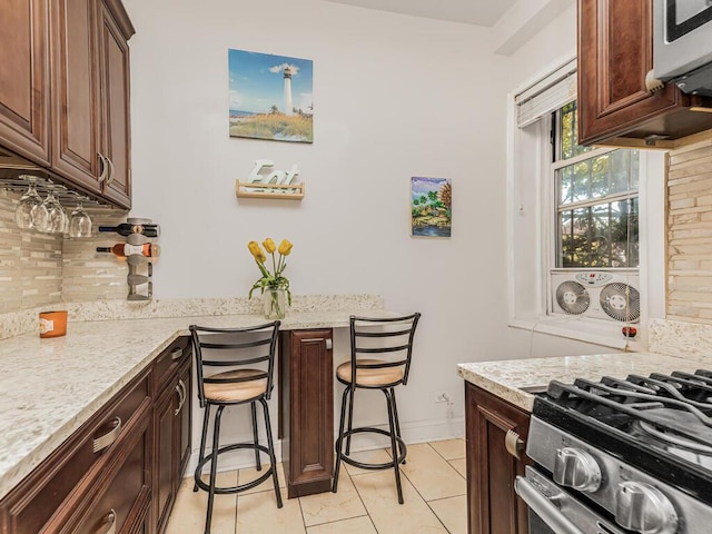 5601 Riverdale Ave Unit 1C, Bronx, NY 10471 - kitchen with decorative backsplash, stainless steel appliances, light stone counters, baseboards, and light tile patterned floors