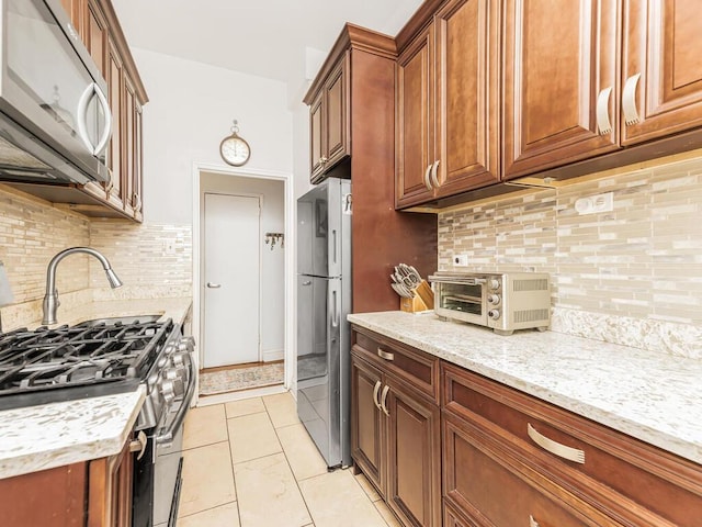 5601 Riverdale Ave Unit 1C, Bronx, NY 10471 - kitchen with stainless steel appliances, light stone counters, backsplash, and brown cabinets