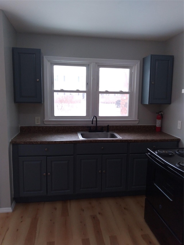 kitchen featuring sink, black electric range, and light wood-type flooring