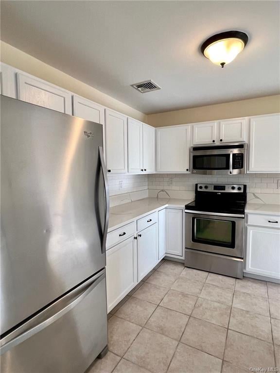 kitchen with backsplash, white cabinetry, stainless steel appliances, and light tile patterned floors