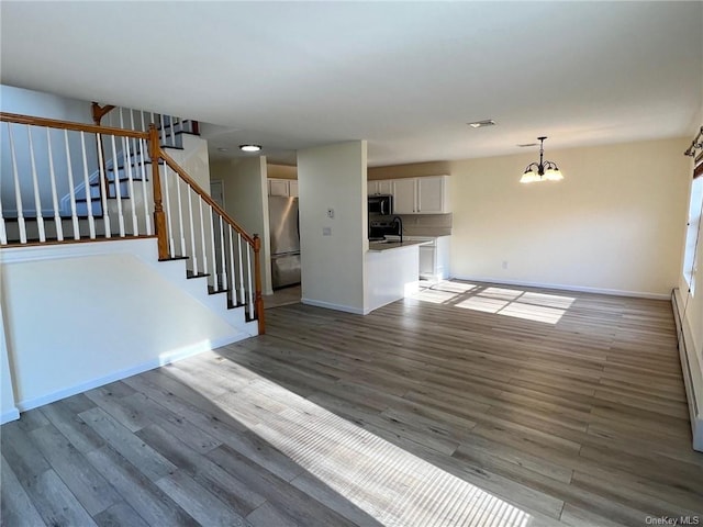 unfurnished living room with sink, a notable chandelier, and light wood-type flooring