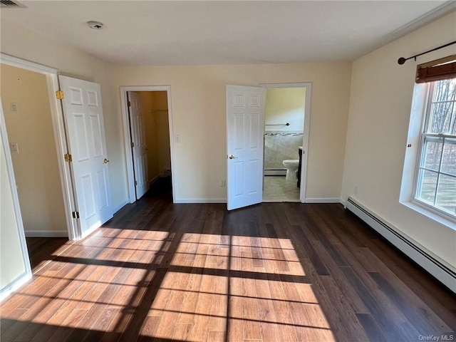 unfurnished bedroom featuring baseboard heating, ensuite bathroom, and dark hardwood / wood-style floors