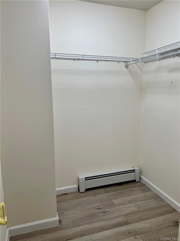 spacious closet featuring light wood finished floors and a baseboard heating unit