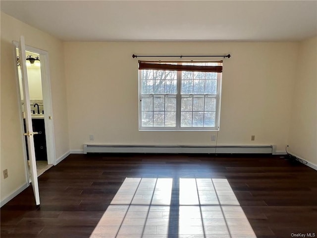 spare room with a sink, baseboards, baseboard heating, and dark wood-type flooring