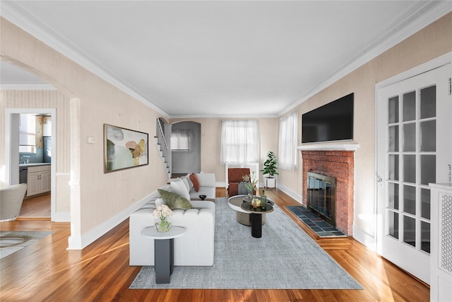 living room with crown molding, wood-type flooring, and a fireplace