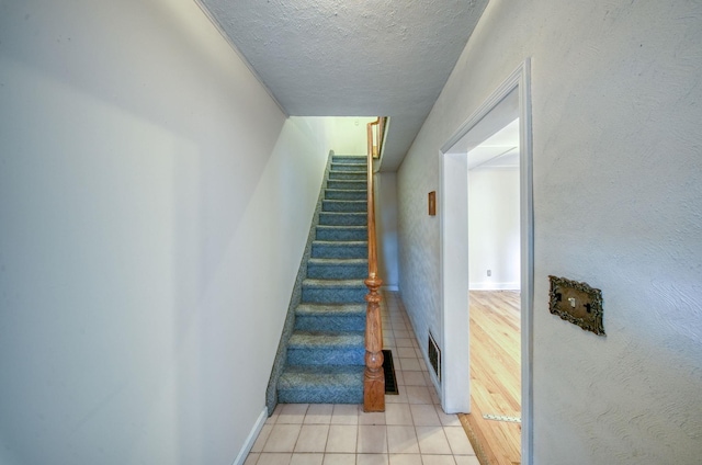 stairs featuring tile patterned flooring and a textured ceiling