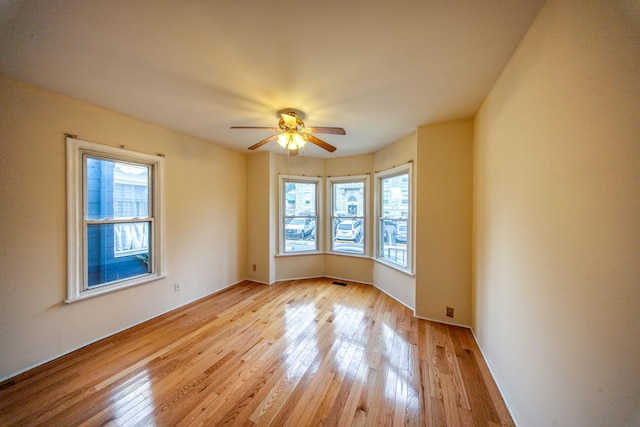 unfurnished room featuring ceiling fan, light hardwood / wood-style flooring, and a healthy amount of sunlight