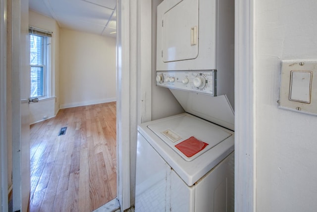 laundry room featuring light hardwood / wood-style flooring and stacked washer / drying machine