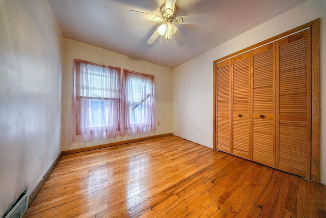 unfurnished bedroom with baseboard heating, ceiling fan, a closet, and light wood-type flooring