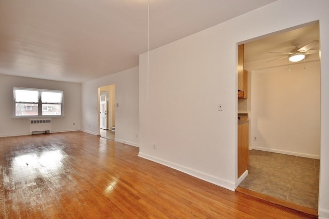 unfurnished room with radiator, ceiling fan, and light hardwood / wood-style flooring