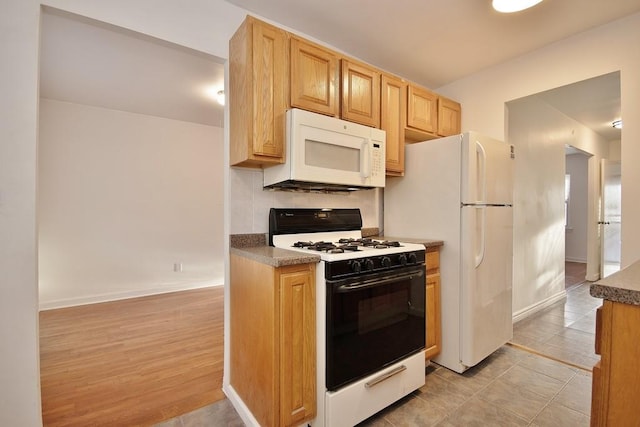 kitchen featuring light brown cabinetry, white appliances, light hardwood / wood-style floors, and tasteful backsplash