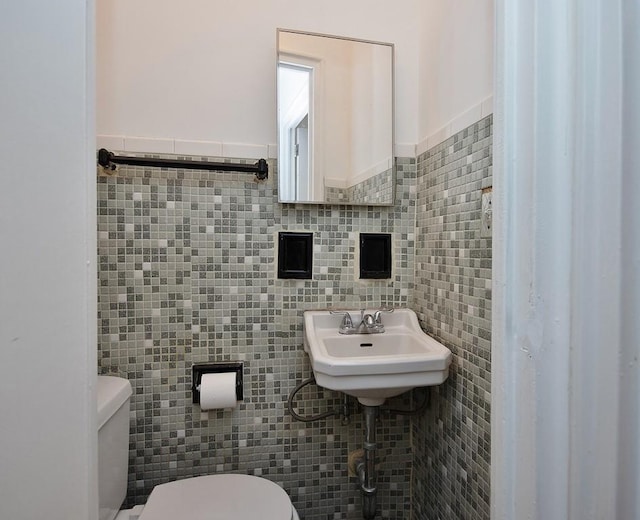 bathroom featuring sink, toilet, and tile walls