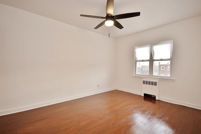 unfurnished room with hardwood / wood-style flooring, ceiling fan, and radiator heating unit