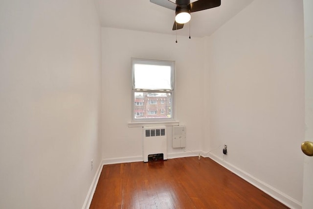 spare room with ceiling fan, wood-type flooring, and radiator heating unit