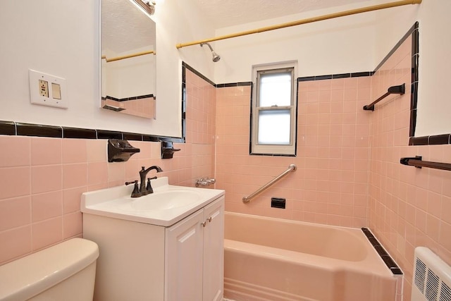 full bathroom featuring vanity, toilet, tile walls, and tiled shower / bath combo