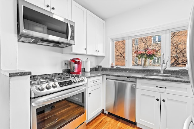 kitchen featuring light wood finished floors, white cabinetry, stainless steel appliances, and a sink