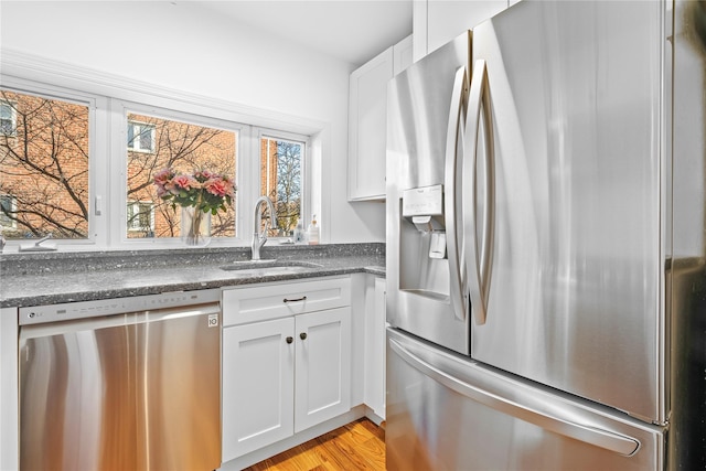 kitchen featuring light wood-type flooring, white cabinetry, stainless steel appliances, and a sink