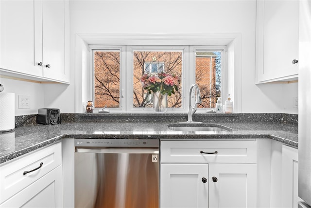 kitchen featuring dark stone counters, white cabinets, dishwasher, and a sink