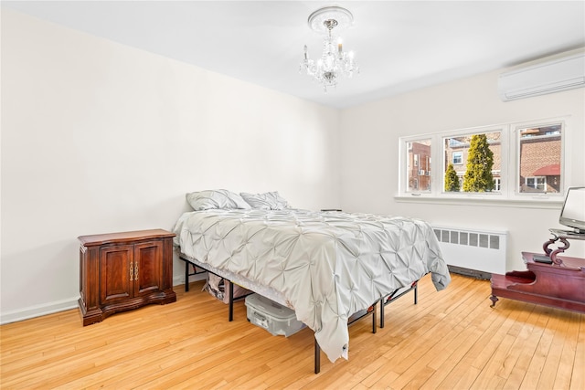 bedroom with light wood-style flooring, radiator, an AC wall unit, and an inviting chandelier