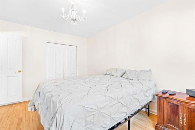 bedroom featuring a closet, baseboards, a notable chandelier, and light wood finished floors