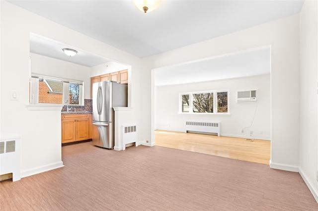 kitchen featuring freestanding refrigerator, an AC wall unit, and radiator heating unit