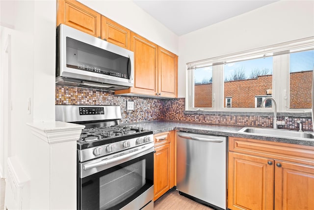 kitchen with dark countertops, appliances with stainless steel finishes, decorative backsplash, and a sink