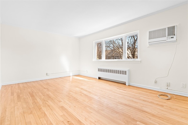 unfurnished room with radiator, a wall mounted AC, ornamental molding, wood finished floors, and baseboards