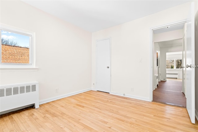 unfurnished bedroom featuring light wood finished floors and radiator heating unit