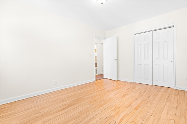 unfurnished bedroom featuring light wood-style floors, baseboards, and a closet