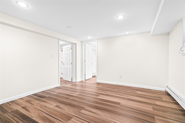 empty room with light wood finished floors, a baseboard radiator, recessed lighting, and baseboards