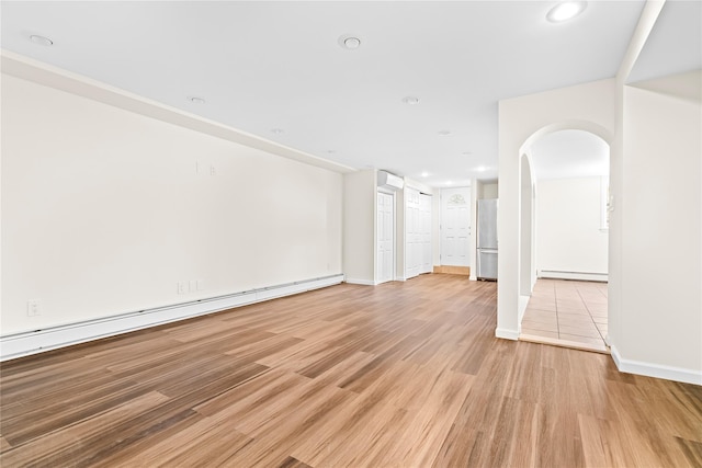 unfurnished living room featuring light wood-style floors, a baseboard radiator, arched walkways, and recessed lighting