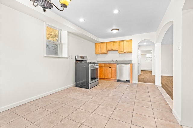 kitchen with light countertops, appliances with stainless steel finishes, light tile patterned flooring, and baseboards