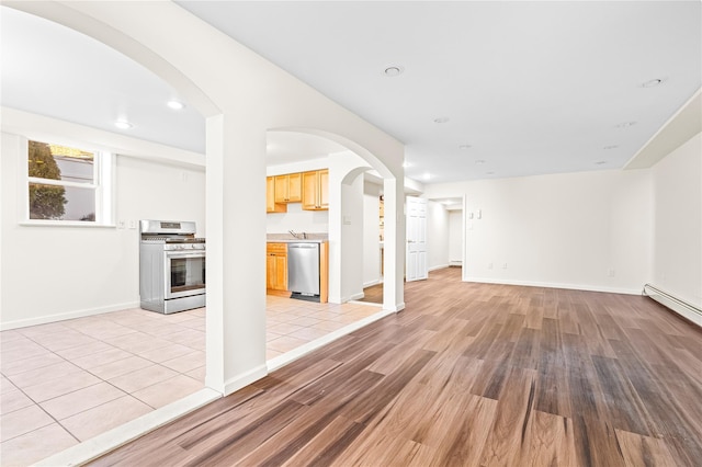 unfurnished living room featuring recessed lighting, baseboards, arched walkways, and light wood finished floors