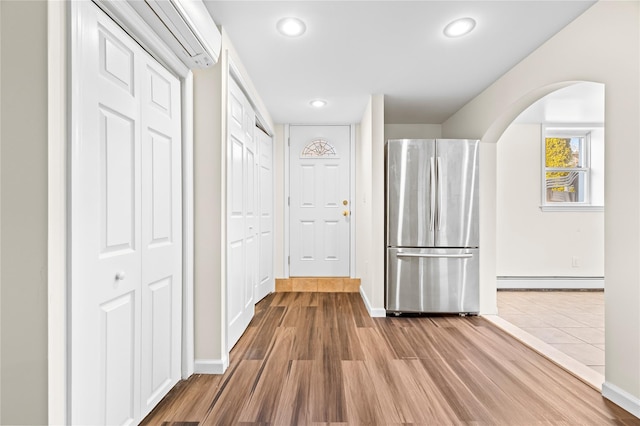 hall featuring baseboards, arched walkways, a baseboard radiator, wood finished floors, and recessed lighting