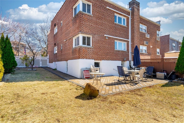 rear view of property featuring brick siding, a patio, a chimney, a lawn, and a fenced backyard