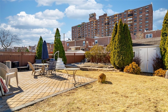 view of patio / terrace with an outbuilding, a shed, and fence