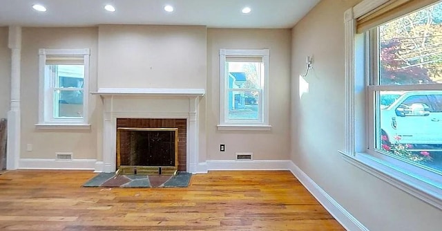 unfurnished living room featuring a fireplace, a wealth of natural light, and light hardwood / wood-style flooring