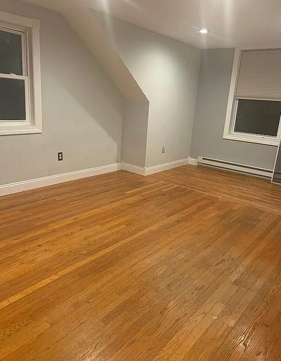 bonus room with baseboard heating and light hardwood / wood-style floors