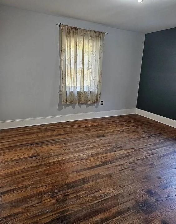 unfurnished room with dark wood-type flooring