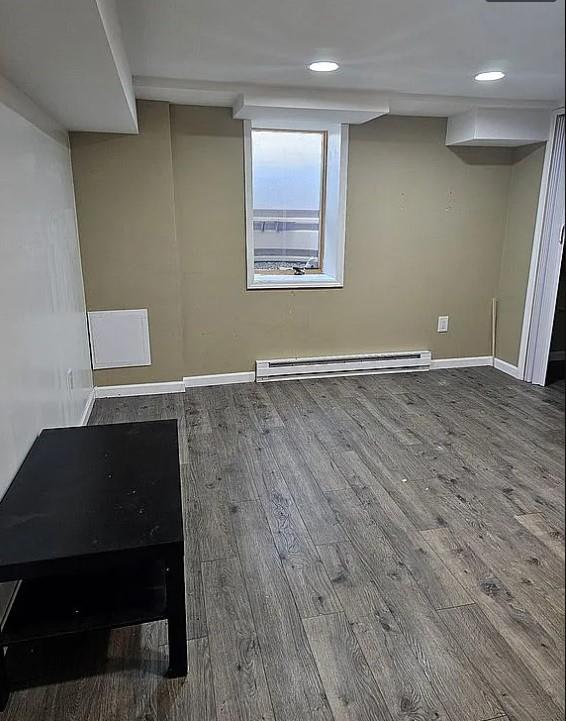 basement featuring baseboard heating and hardwood / wood-style floors