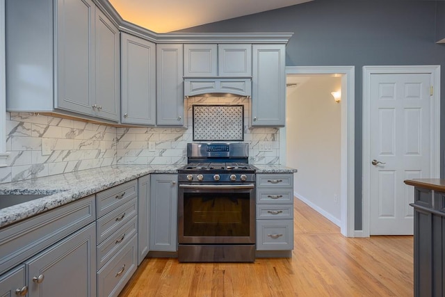 kitchen with decorative backsplash, lofted ceiling, light hardwood / wood-style flooring, and stainless steel range oven