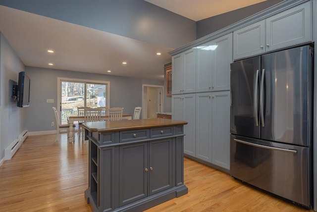 kitchen with a kitchen island, light hardwood / wood-style flooring, stainless steel refrigerator, and gray cabinetry