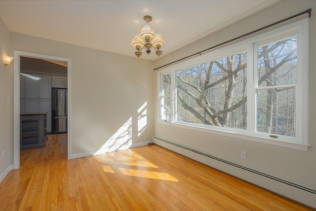 unfurnished room with plenty of natural light, wood-type flooring, and a baseboard radiator