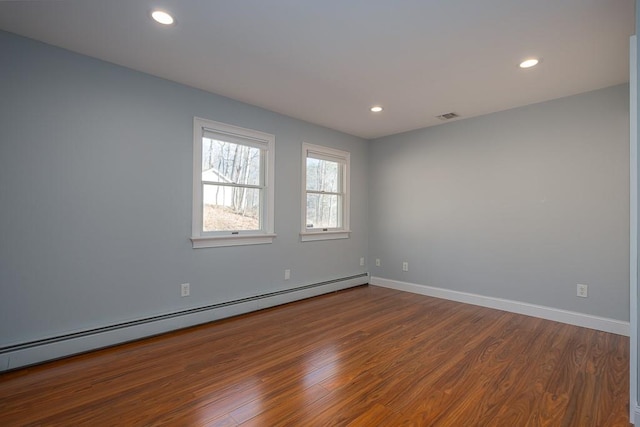 empty room with hardwood / wood-style flooring and baseboard heating