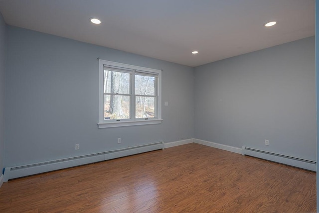 unfurnished room with hardwood / wood-style flooring and a baseboard heating unit